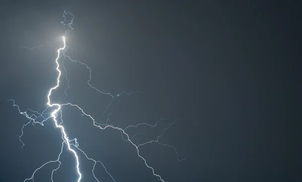 Powerful lightning strikes the ground during big storm. Slight noise due to long exposure — Stock Photo, Image