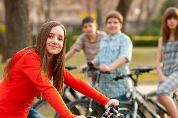 Vacker tonårsflicka umgås med sina vänner ridning cyklar — Stockfoto