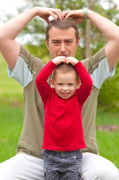Far imiterar sin son medan spendera tid i parken — Stockfoto