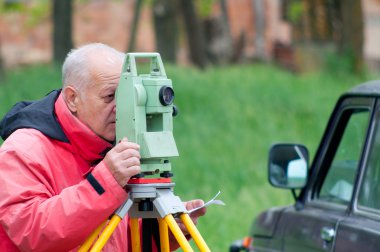 Land surveyor measuring with total station on construction site clipart