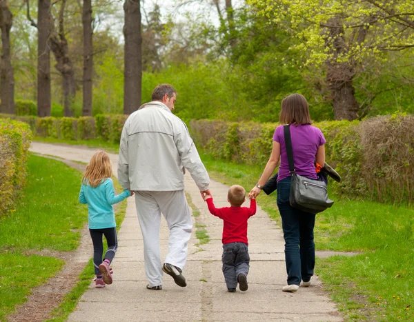 Jovem família caminhando no parque no dia nublado da primavera — Fotografia de Stock