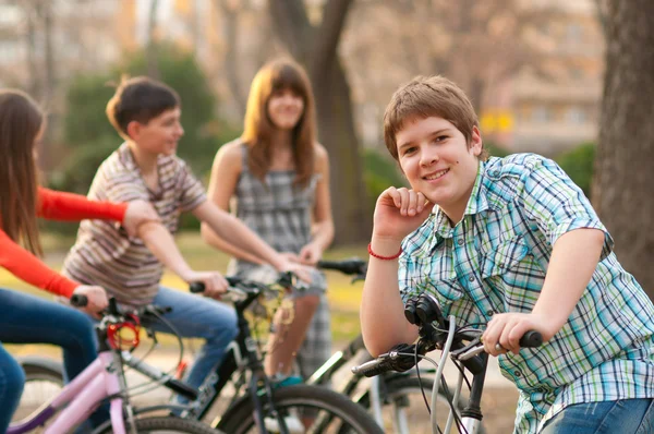 Glad tonårspojke umgås med sina vänner ridning cyklar — Stockfoto