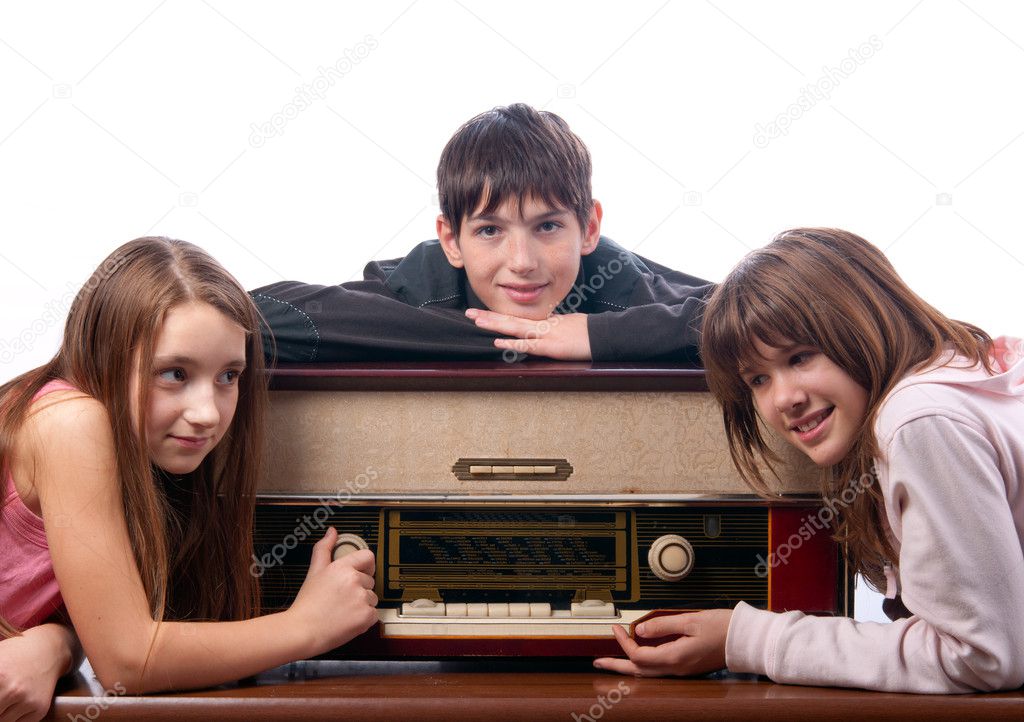 Three teenage friends listening to music on the old radio isolated on white