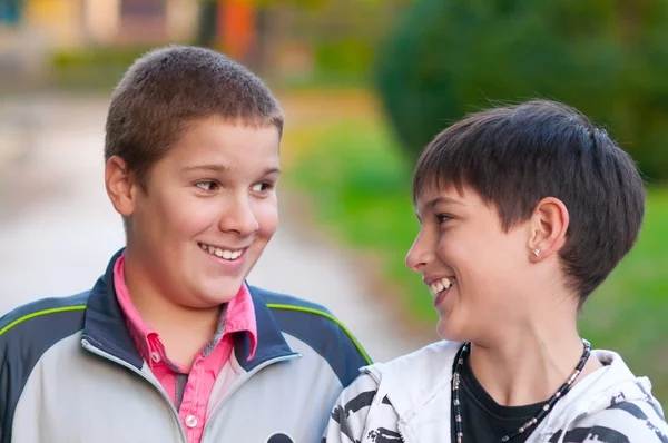 Due ragazzi adolescenti ridono e scherzano nel parco in una bella giornata autunnale — Foto Stock