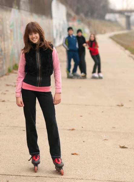 Hübsches lächelndes Mädchen posiert draußen mit Freunden im Hintergrund — Stockfoto