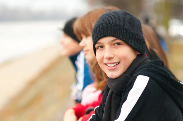 バック グラウンドで友達と外の 10 代の少年の笑顔がかわいい — ストック写真