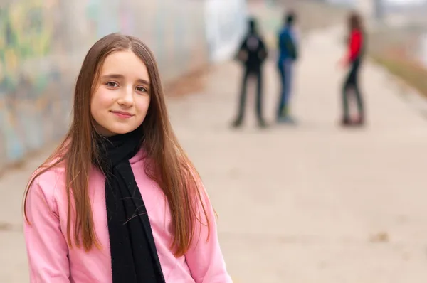 Docela usměvavá dívka pózuje venku s přáteli v pozadí — Stock fotografie