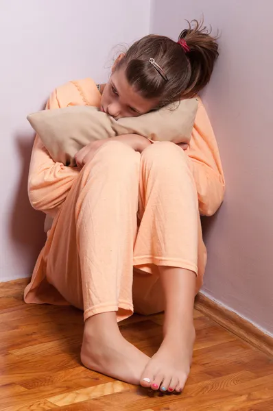 Pretty sad teenage girl curled up in the corner of the room — Stock Photo, Image