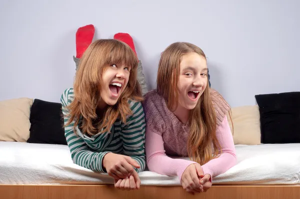 Bardzo nastoletnie dziewczyny robiąc Śmieszne miny leżąc w łóżku — Zdjęcie stockowe