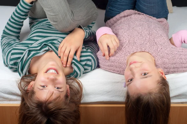 Meninas adolescentes bonitas deitadas na cama com as cabeças penduradas — Fotografia de Stock