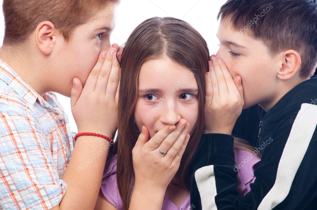 Two cute teenage boys gossiping with teenage girl isolated
