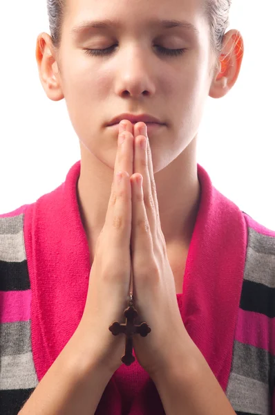 Молодая девушка молится, держа маленький крест между ладонями — стоковое фото