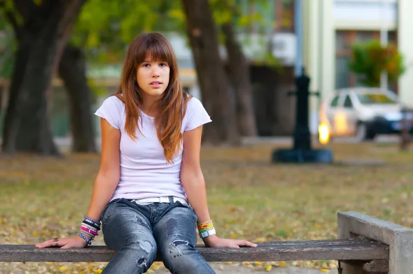 Linda adolescente sentada en el banco en el parque — Foto de Stock