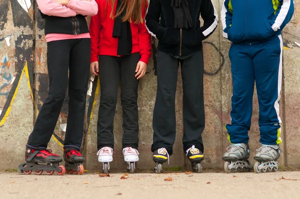 Gruppo di adolescenti in pattini a rotelle in piedi accanto al muro — Foto Stock