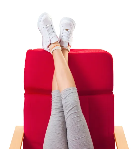 Девушка отдыхает в красном кресле с поднятыми ногами — стоковое фото