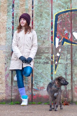 güzel genç kız köpekle bulutlu kış gününde duvara yaslanmış