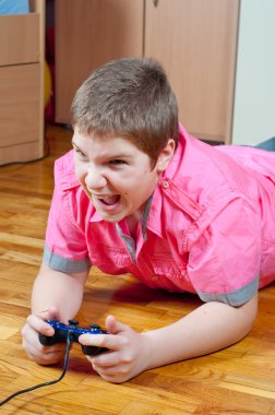 Angry chubby teenage boy playing computer games using game pad clipart