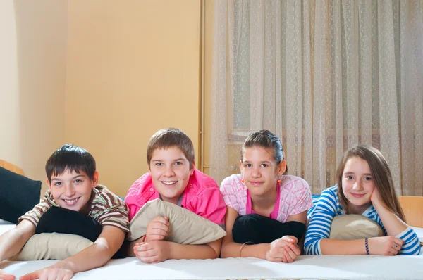 Čtyři happy dospívající přátelé položenou na posteli — Stock fotografie