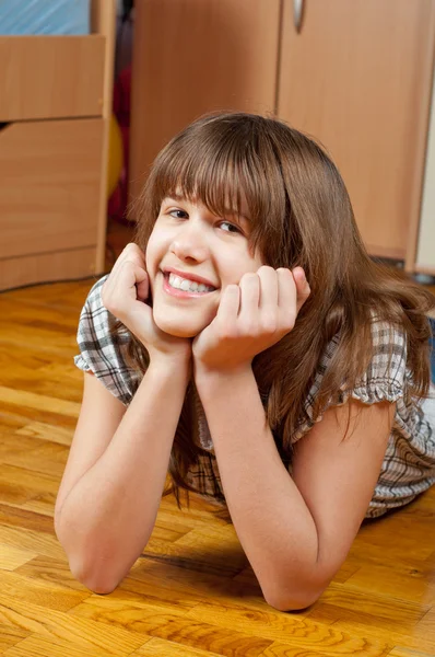Roztomilý usměvavý dospívající dívka leží na dřevěné podlaze svého pokoje — Stock fotografie