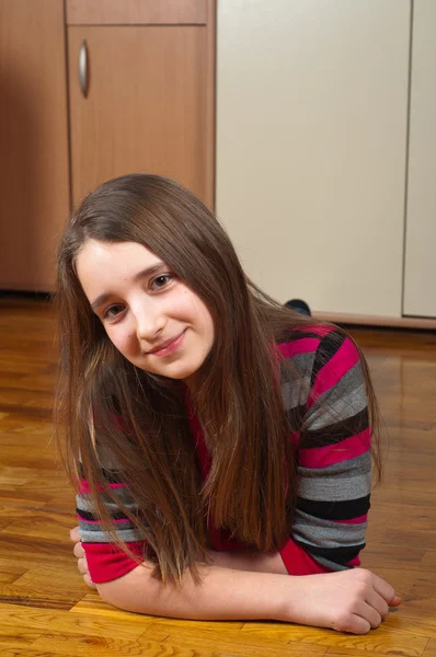 Linda adolescente sonriente acostada en el suelo de madera de su habitación — Foto de Stock