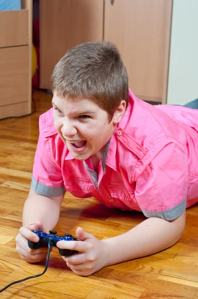 Angry chubby teenage boy playing computer games using game pad — Stock Photo, Image