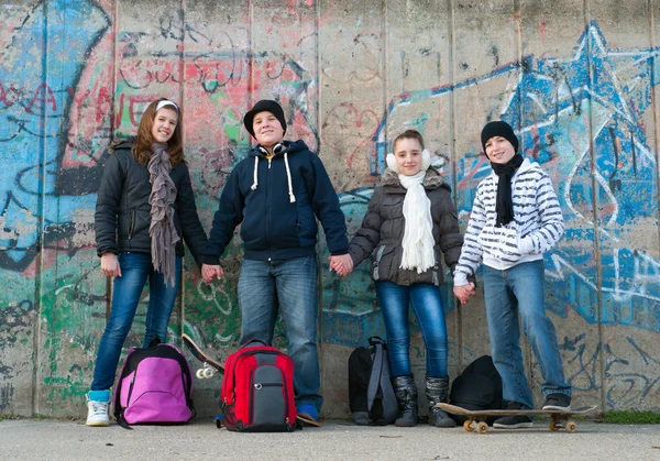 Happy teenage friends with school bags and skateboards standing in front of — Stock Photo, Image