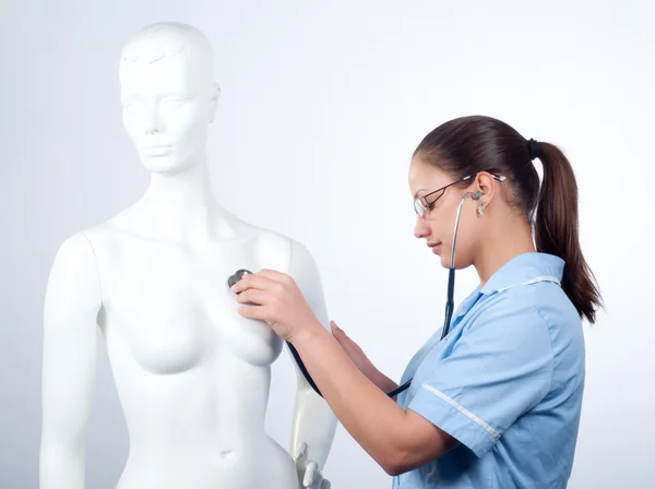 Красивая женщина-врач слушает со стетоскопом куклы сердцебиение — стоковое фото