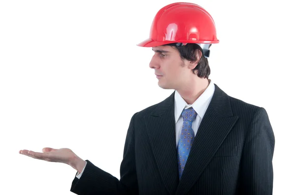 Jovem engenheiro com capacete vermelho segurando objeto imaginado em sua palma aberta isolado em branco — Fotografia de Stock