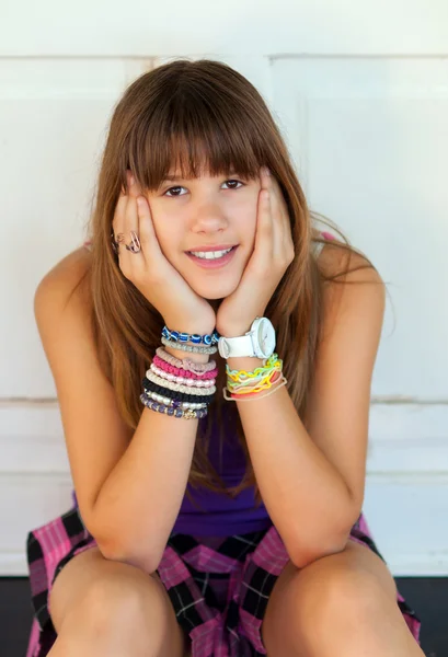 Bella ragazza adolescente sorridente seduta davanti alla porta bianca nella calda giornata estiva — Foto Stock