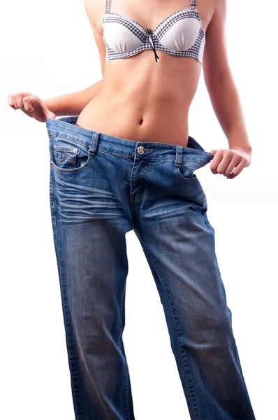 Detail atletické svalnaté ženské tělo v staré kalhoty po hubnutí — Stock fotografie