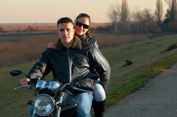 美丽的秋天天日落时分骑摩托车的年轻快乐夫妇 — 图库照片