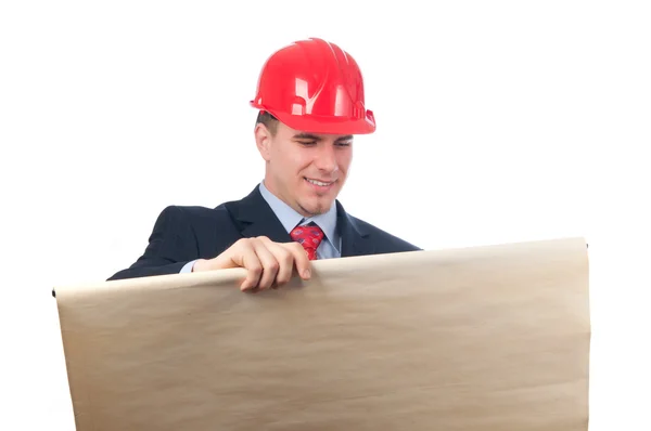 Красивый улыбающийся инженер с красным шлемом на голове, смотрящий на чертеж, изолированный на белом — стоковое фото