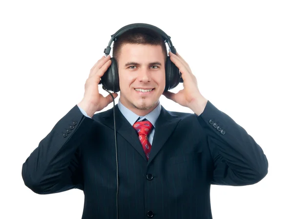 Sonriente hombre de negocios guapo escuchando música a través de los auriculares aislados en blanco —  Fotos de Stock