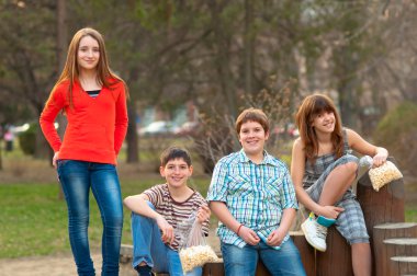 Happy teenage boys and girls spending time together in the park on beautiful spring day clipart