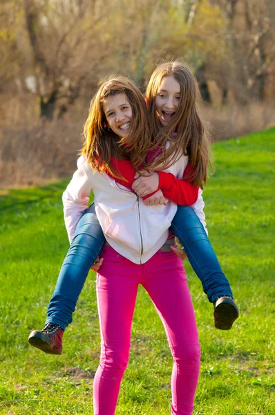 Glücklich Teenager Mädchen huckepack Reiten auf dem schönen sonnigen Frühlingstag — Stockfoto