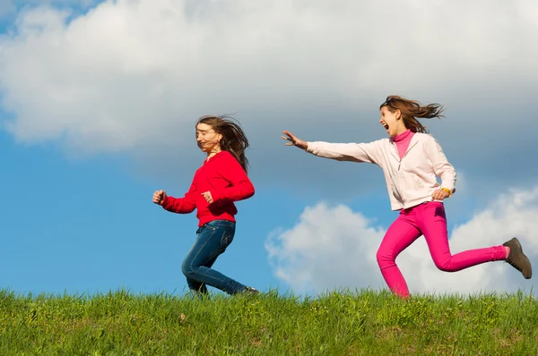 Twee gelukkige tienermeisjes uitgevoerd op de weide op zonnige lentedag — Stockfoto