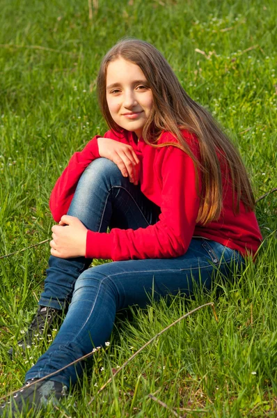 Krásná dospívající dívka sedící v trávě na slunný jarní den — Stock fotografie