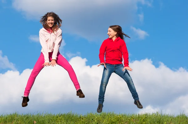 Cute teenage girls jumping with joy on sunny spring day — Stock Photo, Image