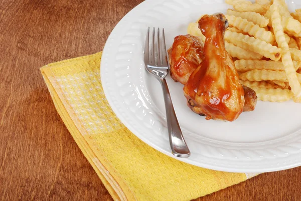 Barbecue chicken legs with fries and yellow napkin — Stock Photo, Image