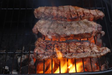 Strip loin steaks on the barbecue clipart