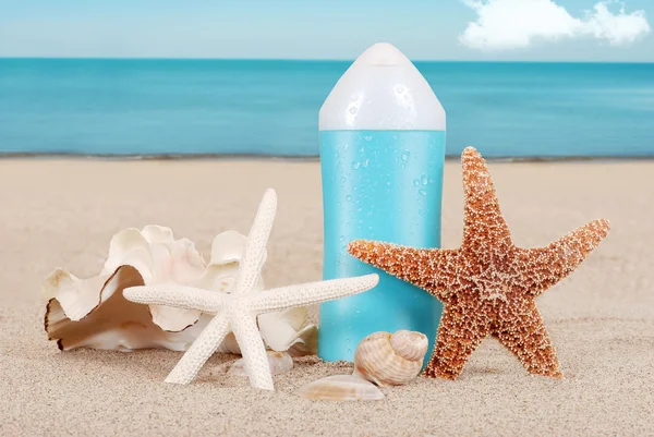 Suntan lotion with shells on the beach — Stock Photo, Image