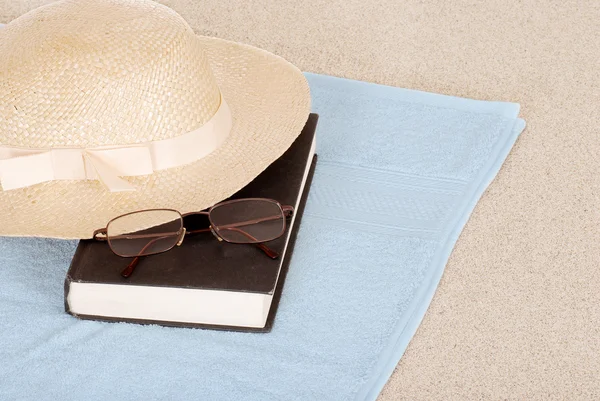 Livro de chapéu de verão e óculos na praia — Fotografia de Stock