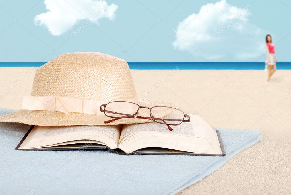 Book glasses and hat on the beach