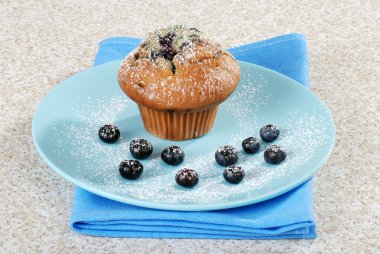 Blueberry muffin on a plate with icing sugar clipart