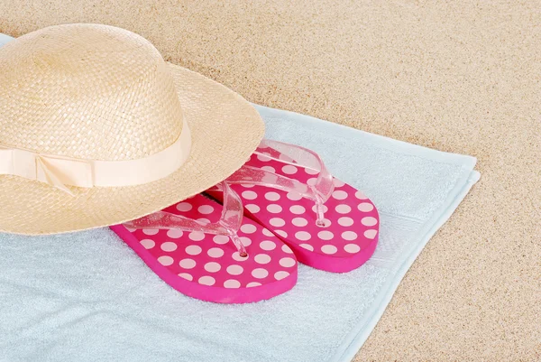 Chapéu de sandálias em uma toalha de praia — Fotografia de Stock