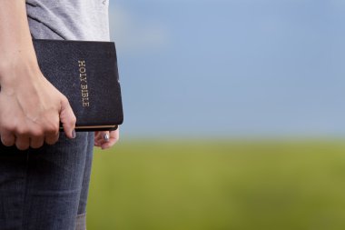 Standing Holding the Bible in a Field