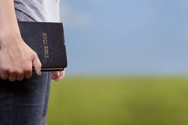 Steht mit der Bibel in der Hand auf einem Feld — Stockfoto