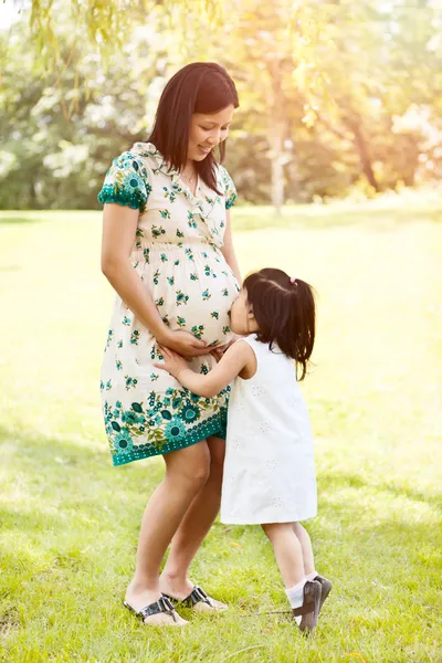Girl kissing pregnant mother — Stock Photo, Image