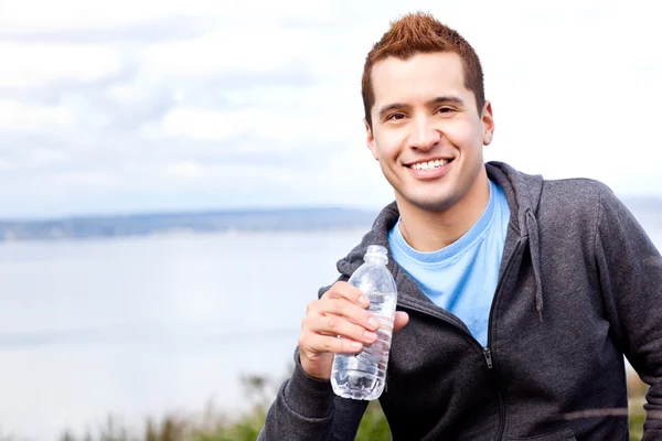 Hombre de raza mixta sosteniendo botella de agua — Foto de Stock