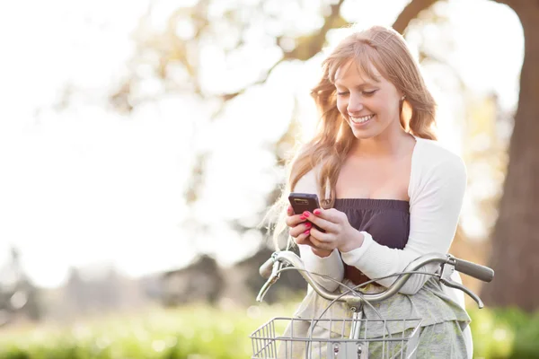 Mulher bonita mensagens de texto em seu telefone ao ar livre — Fotografia de Stock